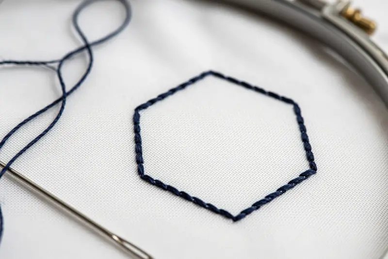 Detalle de bordado en hilo azul sobre tela blanca